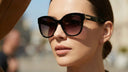 An elegant person wears stylish, luxury Italian sunglasses on a sunny day.