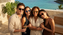 A group of friends wearing sunglasses smiles together in bright sunshine.