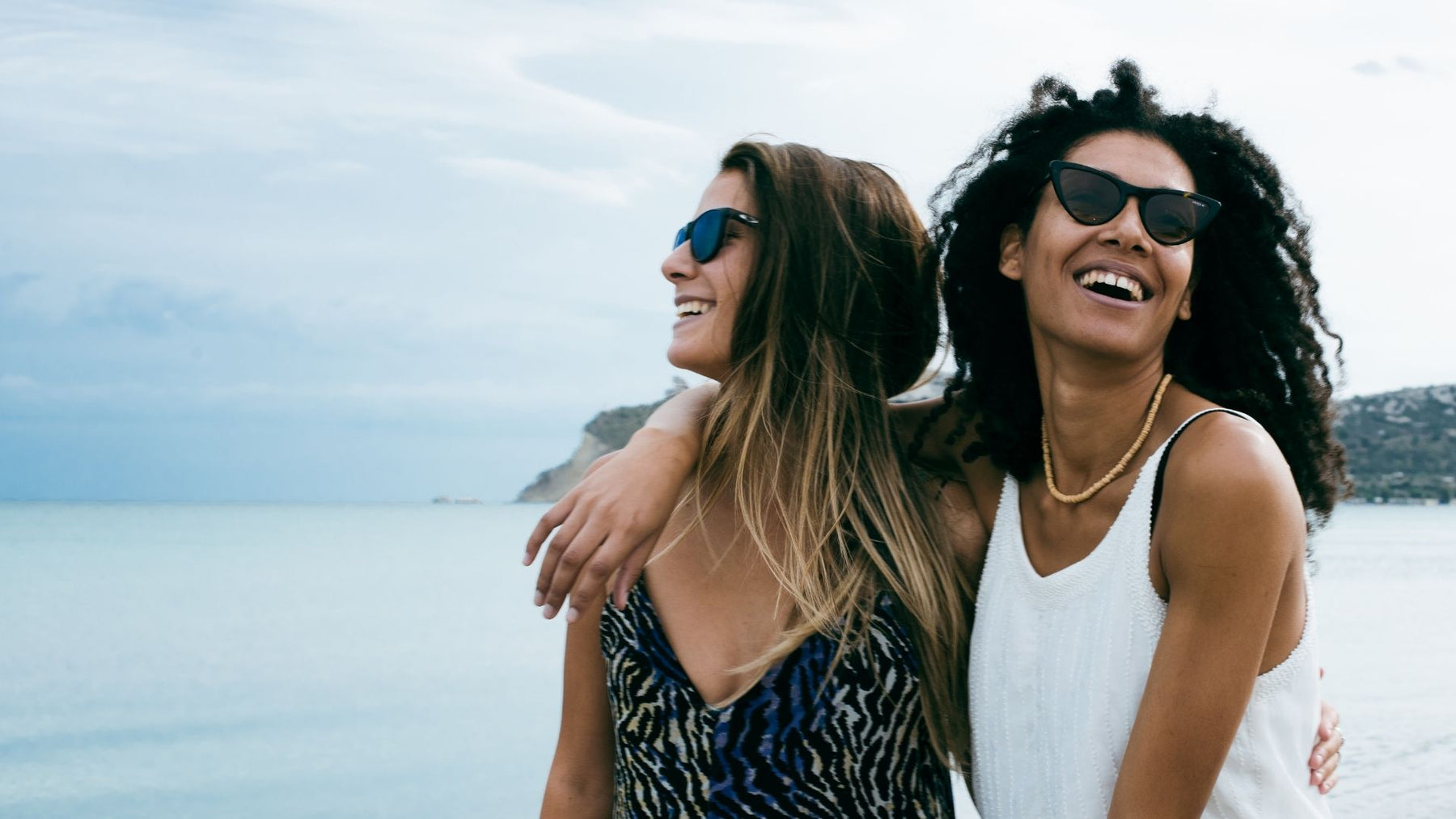 Image of two women wearing sunglasses on the beach