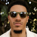 Man wearing green sunglasses with a blurred natural background