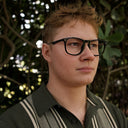 Person wearing glasses with a blurred natural background